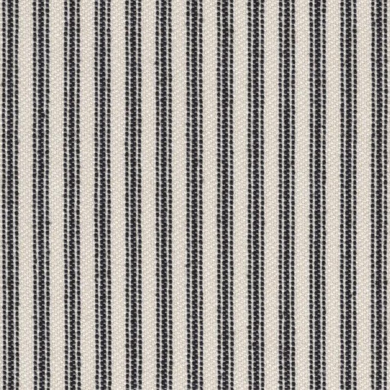 May include: A woven fabric featuring a repeating pattern of vertical black stripes set against a cream-colored background. The design consists of alternating thick and thin dark lines that create a textured, linear appearance across the entire surface.