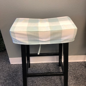 May include: A black bar stool with a light blue and white checkered seat cover.