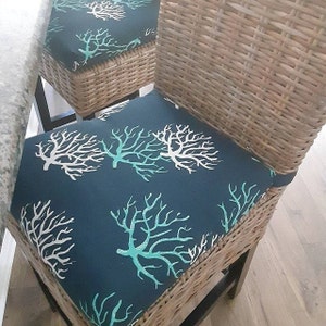 May include: A wicker chair with a dark blue cushion featuring a white and teal coral reef pattern.