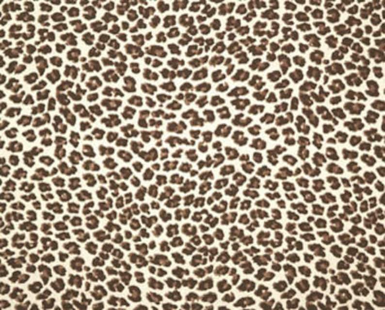 May include: A brown and white leopard print fabric with a repeating pattern of brown spots on a white background.