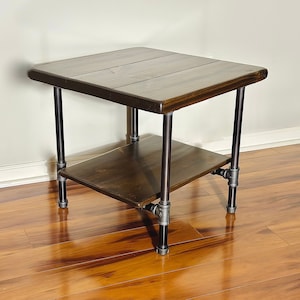 May include: A dark brown wooden end table with a black metal frame and two shelves. The table has a rustic, industrial style.