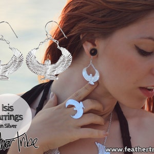 Puede incluir: Pendientes de plata con un dise&ntilde;o detallado de la diosa egipcia Isis con las alas extendidas. Los pendientes son de aro y tienen cierre de gancho. El texto "Isis Earrings in Silver" y "Feather Tribe" es visible en la imagen.