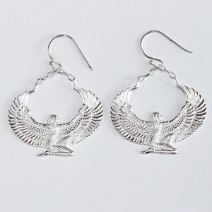 Puede incluir: Pendientes de plata con un dise&ntilde;o detallado de una diosa alada con las alas extendidas. Los pendientes son de aro y tienen un cierre de gancho.