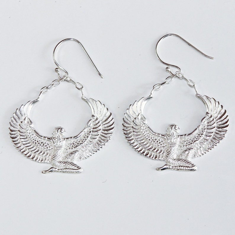 Puede incluir: Pendientes de plata con un dise&ntilde;o detallado de una diosa alada con las alas extendidas. Los pendientes son de aro y tienen un cierre de gancho.