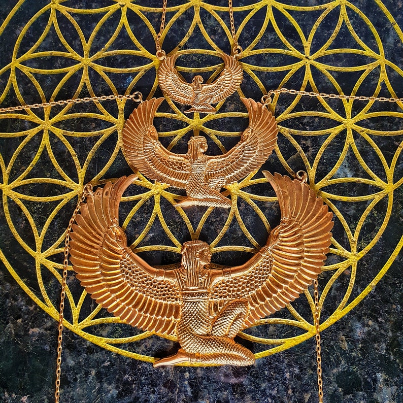 Puede incluir: Tres collares de color dorado con un dise&ntilde;o de diosa alada. Los collares est&aacute;n superpuestos sobre un fondo negro con un patr&oacute;n geom&eacute;trico dorado.
