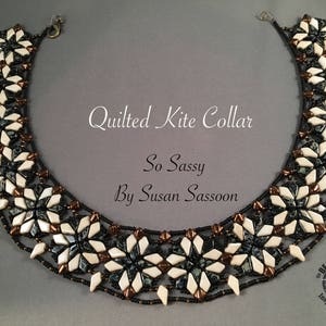 Puede incluir: Un collar de cuentas negro y blanco con un patrón geométrico. El collar se llama "Quilted Kite Collar" y está diseñado por Susan Sassoon. El collar está hecho con cuentas negras, blancas y de cobre.