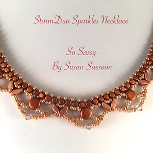 Może przedstawiać: Naszyjnik z koralików miedzianych i złotych z wzorem liści. Naszyjnik nazywa się "Storm Duo Sparkles Necklace" i jest od "So Sassy by Susan Sassoon".