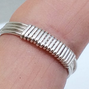 May include: A silver ring made of multiple strands of wire woven together to create a textured band.