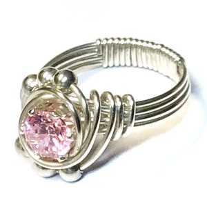May include: A silver wire wrapped ring with a pink gemstone in the center.
