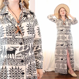 Puede incluir: Un vestido largo blanco con un estampado geométrico en blanco y negro que presenta ciervos, pájaros y árboles. El vestido tiene manga larga, cierre frontal con botones y una abertura lateral. La modelo lleva un sombrero de paja.