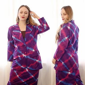 May include: A purple, pink, and blue tie-dye blazer and skirt set. The blazer has a single button closure and a pocket on the left side. The skirt is a pencil skirt.
