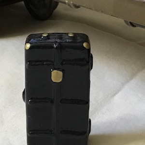 May include: A small black suitcase with gold accents and a textured surface.