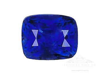 Pode incluir: Uma gema de safira azul escura com corte almofada. A gema tem uma ligeira forma retangular e está engastada em um anel.