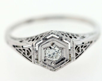 May include: A silver ring with a delicate filigree design and a single round diamond in the center.