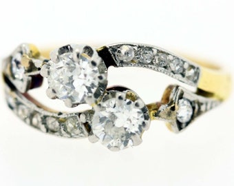 May include: A gold and silver ring with three round diamonds set in a curved band.