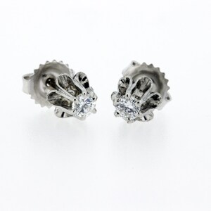 May include: A pair of silver stud earrings with a clear round gemstone set in a floral design.