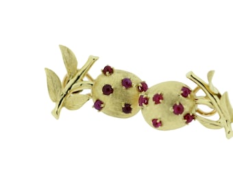 May include: Gold earrings with a leaf design and red ruby stones.