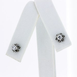 May include: A pair of silver stud earrings with a single clear diamond in each setting.
