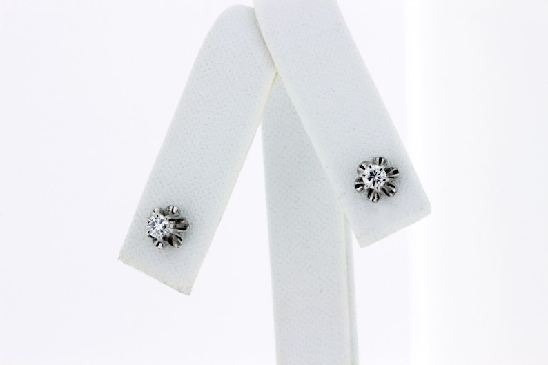 May include: A pair of silver stud earrings with a single clear diamond in each setting.