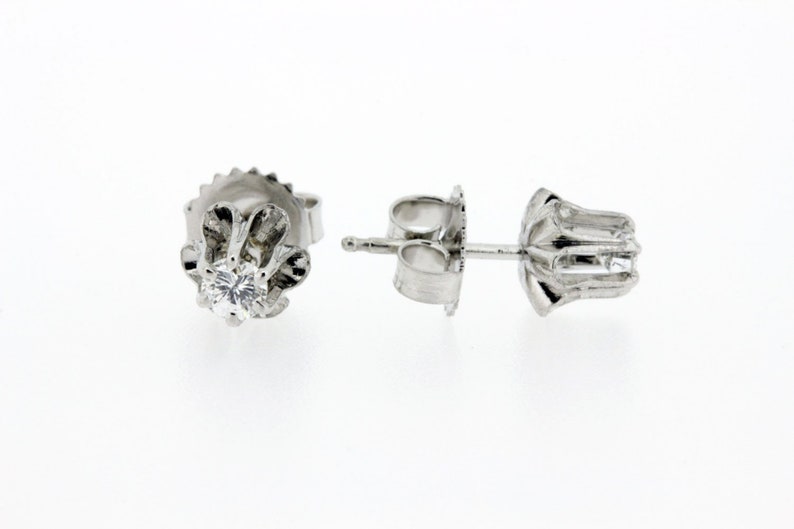 May include: A pair of silver stud earrings with a single round diamond in each earring.