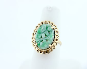 May include: A green jade ring with a carved floral design set in a gold filigree setting.