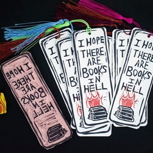 May include: A set of six bookmarks with the text "I hope there are books in hell" printed on them. The bookmarks are white with black text and a red flame illustration. Each bookmark has a different coloured tassel.