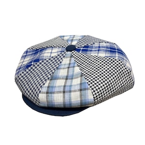 Pode incluir: Um bon&eacute; de newsboy em patchwork azul e branco com uma aba azul marinho.