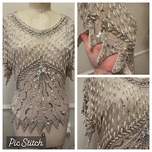 May include: A white beaded top with silver sequins and a fringe design. The top is on a white dress form. The image is split into three sections, showing the front, side, and close-up of the beading.