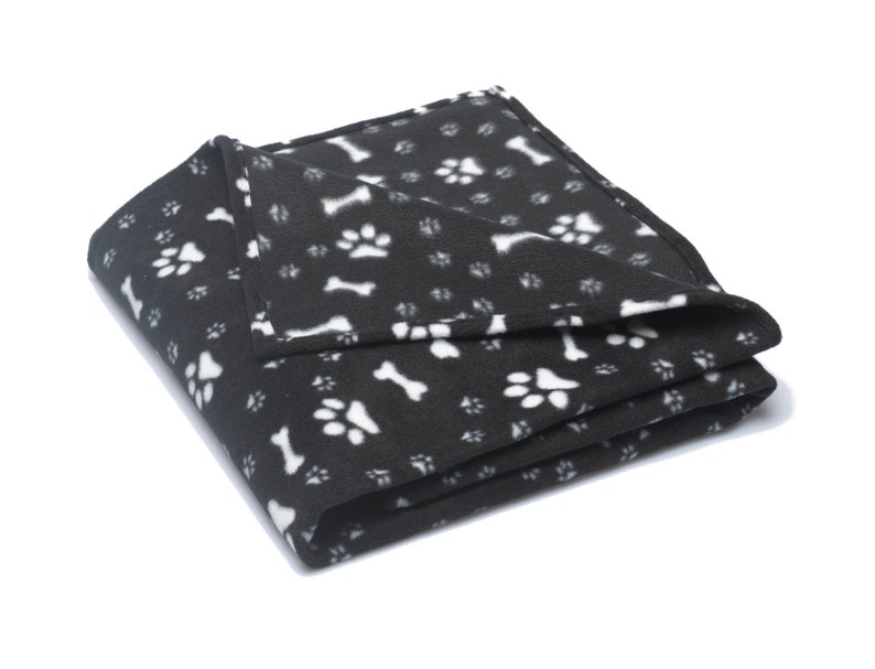 K&ouml;nnte beinhalten: Schwarze Fleece-Hundedecke mit einem wei&szlig;en Pfoten- und Knochenmuster.
