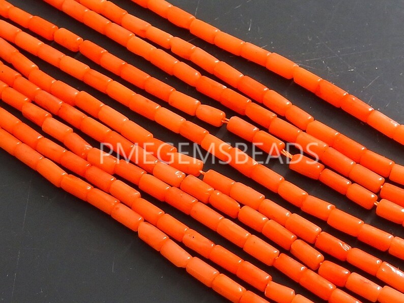May include: Multiple strands of bright orange cylindrical beads arranged in parallel lines. Each bead has a smooth, uniform shape and is strung together. The text PMEGEMSBEADS is overlaid in white across the center of the orange bead strands.