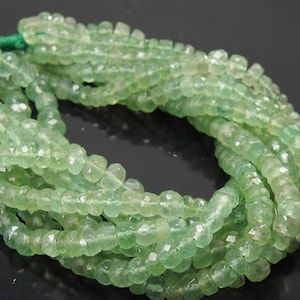 May include: A strand of faceted, translucent light green gemstone beads arranged in a circular loop. The small, round, disc-shaped beads feature a polished finish and are strung together on a thin green thread, creating a continuous, uniform chain.
