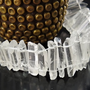 May include: A strand of clear quartz crystal points, strung together with white thread. The points are various lengths and have a natural, raw look.