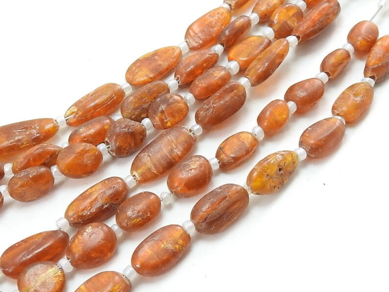 May include: A strand of amber beads with a natural, irregular shape. The beads are a warm, honey-brown color and have a glossy finish.