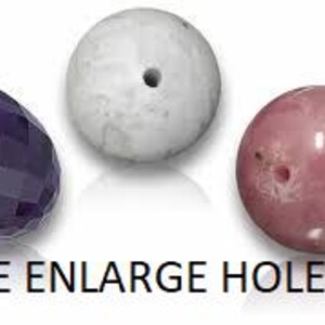 May include: Three beads including a faceted purple teardrop bead, a smooth white spherical bead with a center hole, and a smooth pink spherical bead with a visible hole. The text FREE ENLARGE HOLES is printed in black at the bottom of the image.