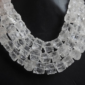 Puede incluir: Un collar de múltiples hileras hecho de cuentas transparentes, facetadas, con aspecto de cristal. Las cuentas son todas de tamaño y forma aproximadamente iguales, y están dispuestas en un patrón escalonado. El collar es una pieza de joyería hermosa y elegante.