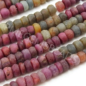 May include: A strand of multi-coloured gemstone beads. The beads are round and have a rough, textured surface. The colours of the beads include pink, red, orange, yellow, green, blue, and purple.