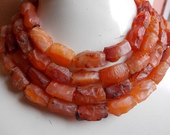 May include: A necklace made of multiple strands of carnelian beads. The beads are a deep orange color and have a natural, irregular shape.