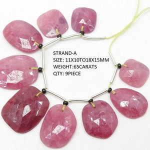 May include: A strand of nine pink ruby gemstone beads, each with a faceted, rectangular shape. The beads are strung on a silver wire with black spacers. The strand is approximately 11x10 to 18x15mm in size and weighs 6.5 carats.  STRAND-A
