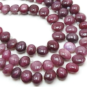 以下が含まれることがあります： 楕円形のピンクのルビービーズのストランド。ビーズは透明な糸に糸に通され、光沢のある仕上げになっています。