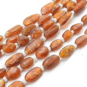 May include: A strand of amber beads with a natural, irregular shape. The beads are a warm, honey-brown color and have a glossy finish.