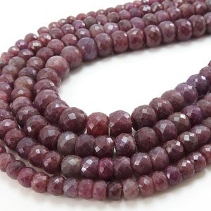 May include: Close-up of multiple strands of deep red-purple gemstone beads. The beads are round and faceted, catching the light. These beads are strung together, ideal for jewellery making or other craft projects.