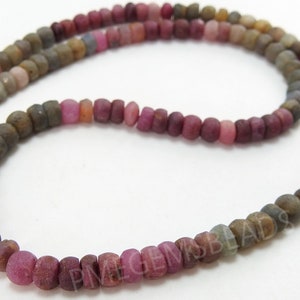 May include: A strand of pink, brown and grey gemstone beads. The beads are round and have a matte finish.