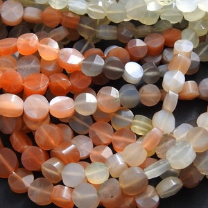 May include: A strand of faceted moonstone beads in shades of white, gray, and orange. The beads are round and have a smooth, polished finish.