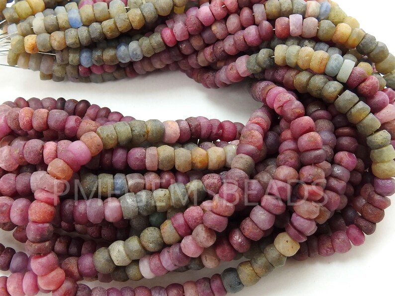 May include: A strand of small, round, multi-coloured gemstone beads. The beads are a mix of pink, red, brown, and grey. The beads are all approximately 4mm in diameter.