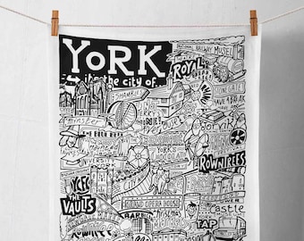 May include: Black and white illustration of the city of York, England. The illustration is filled with landmarks, businesses, and attractions, including the York Minster, the Shambles, the York Chocolate Story, and the York Castle Museum. The text "York in the city of..." is at the top of the illustration.