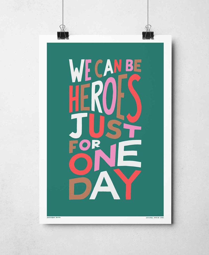 Op de afbeelding: Een tealgroene poster met de tekst "WE CAN BE HEROES JUST FOR ONE DAY" in witte, roze, rode en bruine letters.