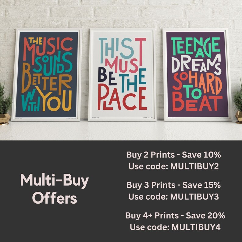 Op de afbeelding: Drie ingelijste prints met kleurrijke typografie. De eerste print heeft een donkerblauwe achtergrond met de tekst "The Music Sounds Better With You". De tweede print heeft een witte achtergrond met de tekst "This Must Be The Place". De derde print heeft een paarse achtergrond met de tekst "Teenage Dreams So Hard To Beat".