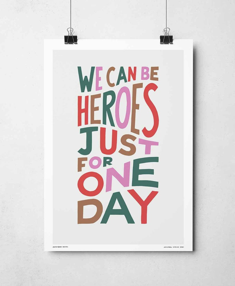 Op de afbeelding: Een motiverende poster met de tekst "We can be heroes just for one day" in kleurrijke, gestileerde letters.