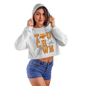 May include: White cropped hoodie with a graphic of the letters "T.U.C.H.O.W.N." in orange with a football helmet and football graphic. The letters "T.U." have a small orange graphic of the state of Tennessee.