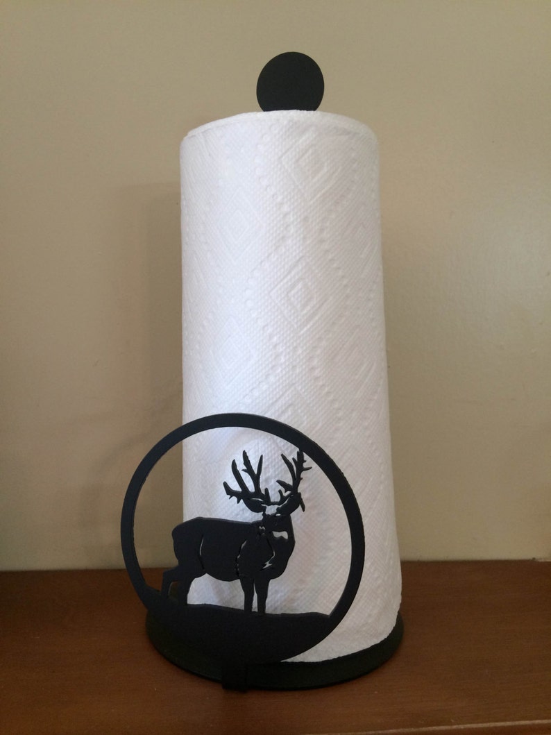 May include: Black metal paper towel holder with a silhouette of a deer. The holder has a round base and a black knob on top.